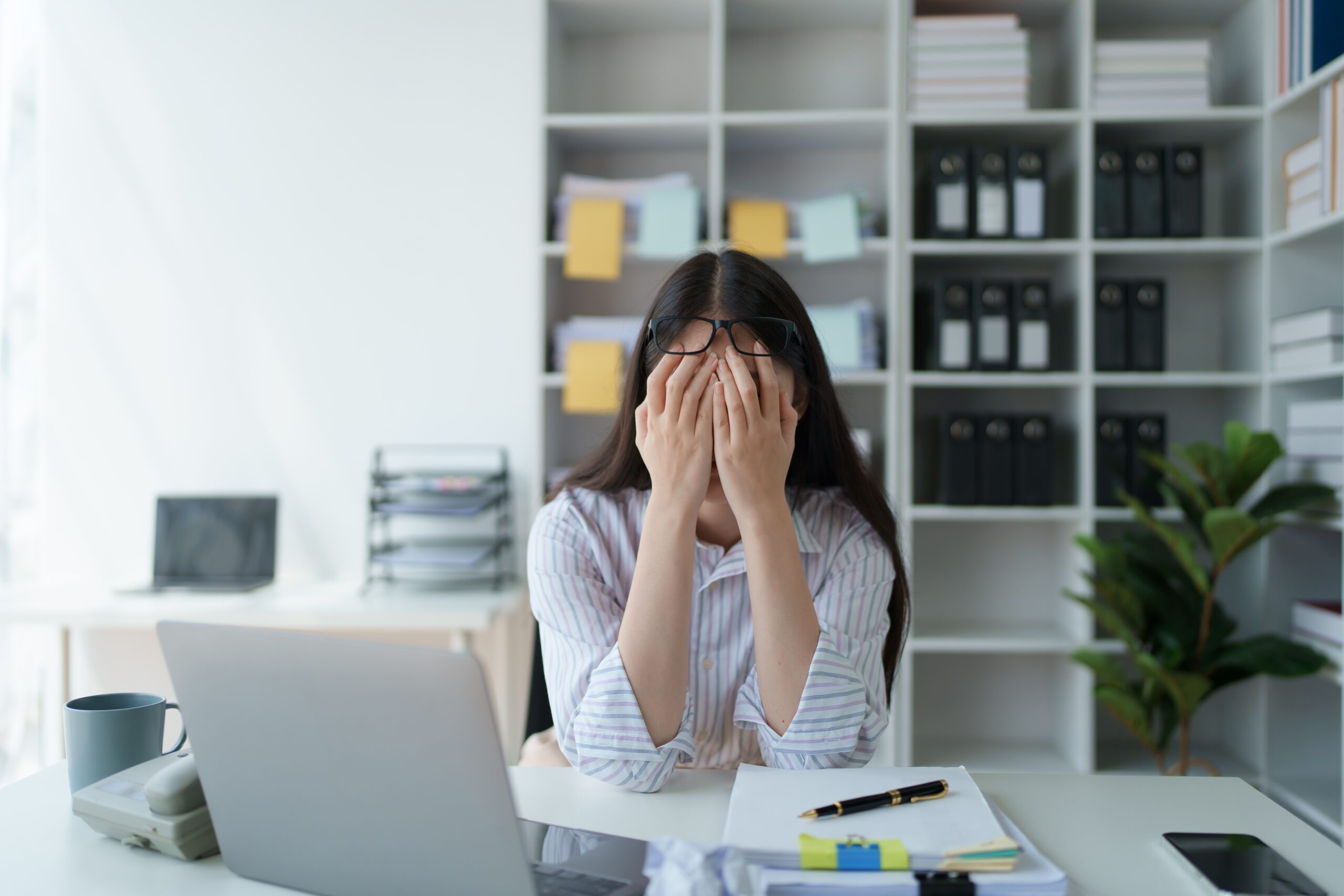 A business professional looking stressed and overwhelmed at her desk.