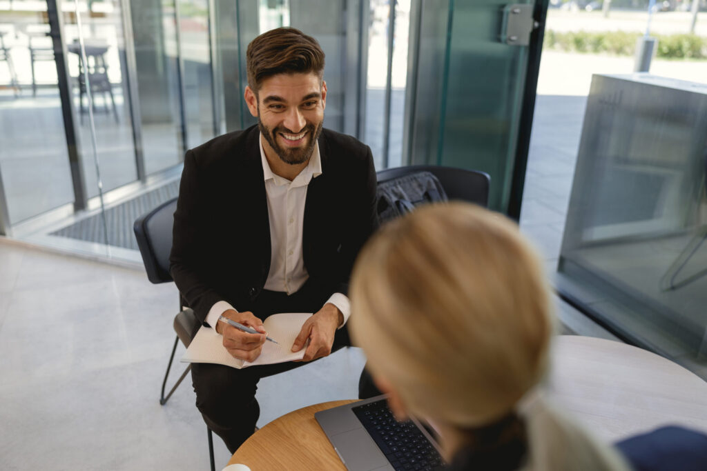 A business professional taking notes while having a positive conversation with a client.