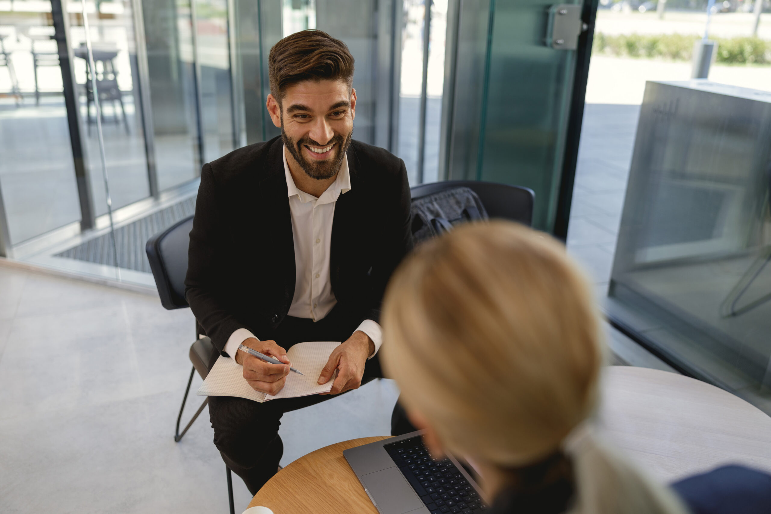 A business professional taking notes while having a positive conversation with a client.