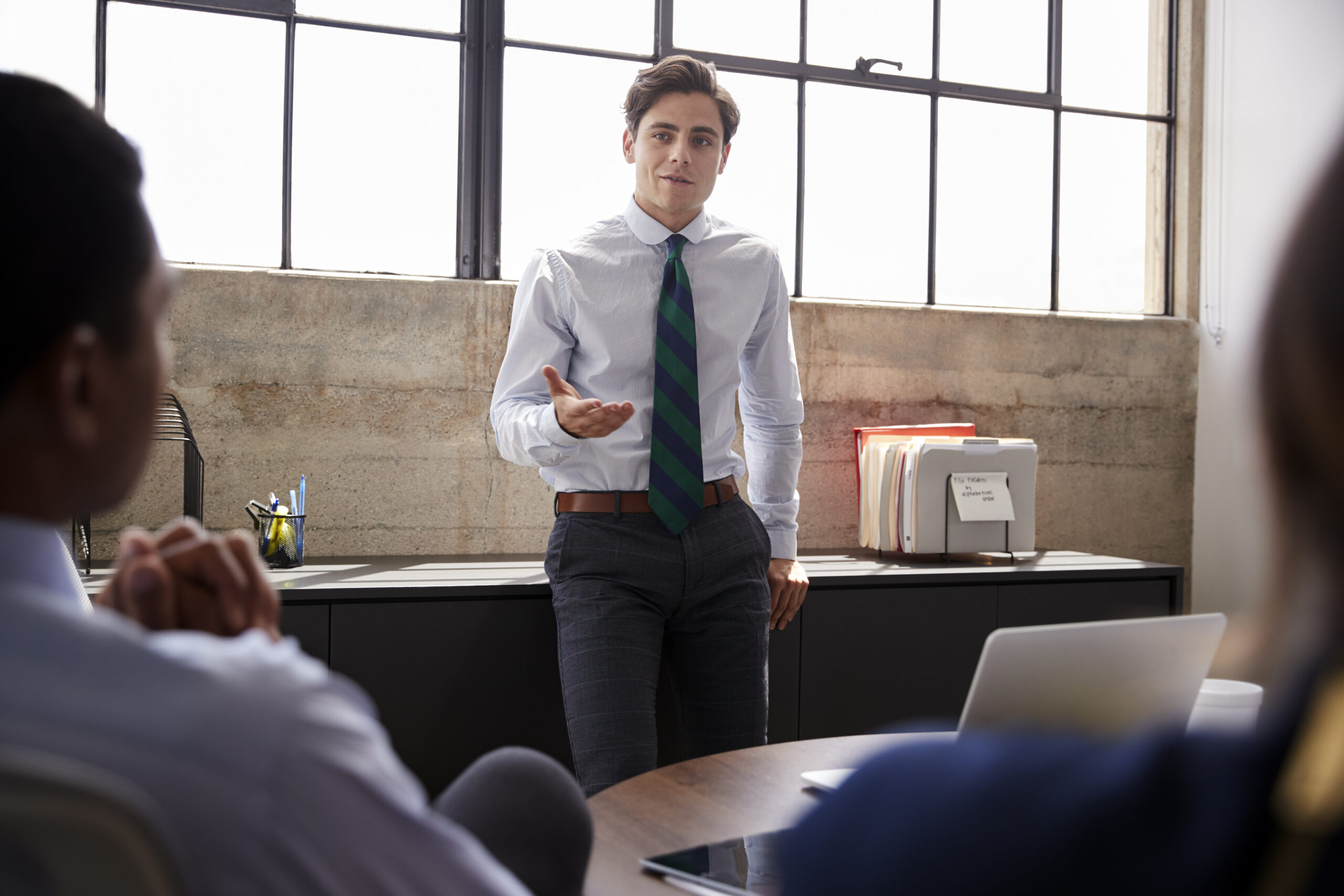 A young professional discussing in front of his colleagues in a modern office environment